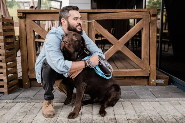 Felice Giovane Uomo Casualwear Seduto Squat Abbracciando Suo Simpatico Cane — Foto Stock