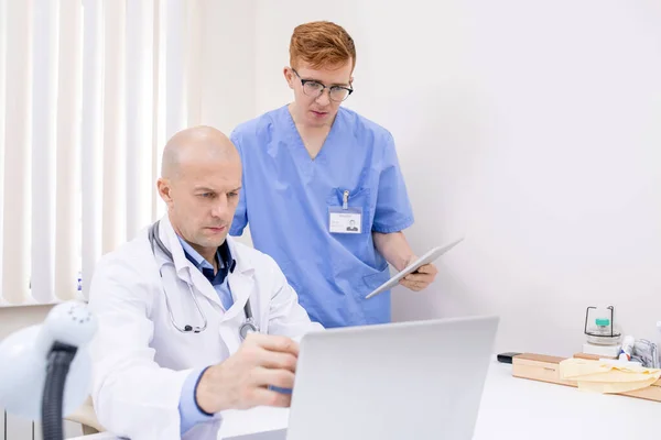 Maturo Medico Fiducioso Che Punta Display Del Computer Portatile Durante — Foto Stock