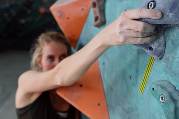 年轻的女攀登者手握住一块人造的小岩石 试图爬上攀登墙的顶端 — 图库照片
