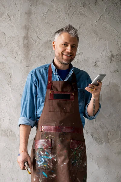 Pintor Feliz Bem Sucedido Com Smartphone Pincel Parede Cinza Estúdio — Fotografia de Stock