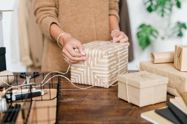 用木桌准备圣诞礼物时 年轻的女性用线把礼品盒包起来 — 图库照片