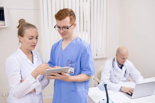 Üniformalı Genç Kliniklerden Biri Online Bilgiyi Meslektaşına Açıklarken Tablet Ekranını — Stok fotoğraf