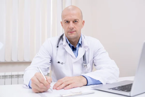 Médico Confiante Meia Idade Careca Whitecoat Sentado Mesa Frente Câmera — Fotografia de Stock