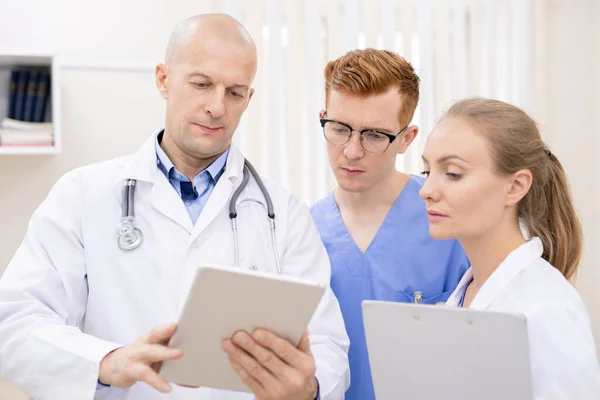 Two Young Serious Interns Listening Attentively Confident Clinician While Looking — Stock Photo, Image