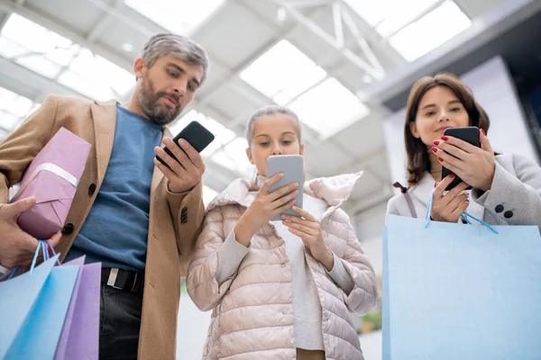 Família Shopaholics Segurando Sacos Papel Presentes Smartphones Enquanto Procura Descontos — Fotografia de Stock