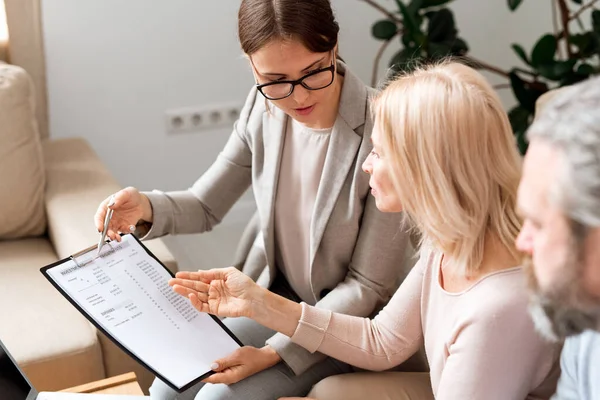 Genç ve olgun kadınlar belgeleri imzalamadan önce müzakere ederken mali harcamalarla kağıt tartışır