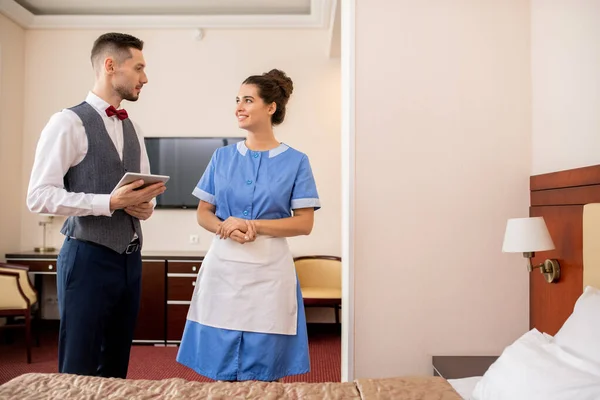 Fröhliche Junge Zimmermädchen Uniform Gespräch Mit Eleganten Portier Mit Touchpad — Stockfoto