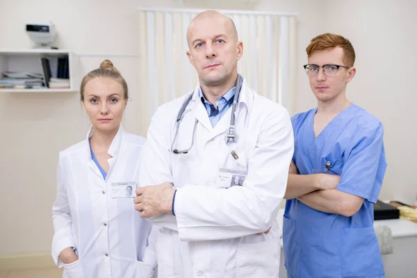 職場でカメラの前に立つ3人の重度の若い成熟したプロの臨床医のグループ — ストック写真
