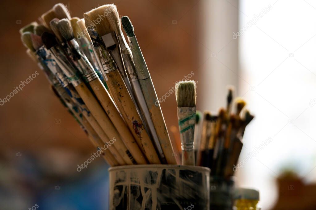 Set of paintbrushes for professional painting in tin can inside modern studio of drawing or classroom in art school