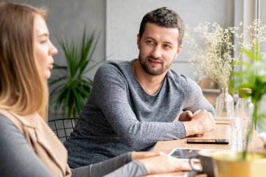Boş zamanlarında kafede kız arkadaşına bakan sıradan kazaklı genç sakallı bir adam.
