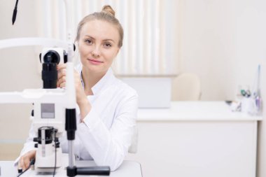 Genç başarılı sarışın optometrist kliniklerde çalışırken yeni göz hastalıkları ekipmanlarını test ediyor.