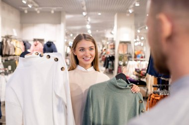 Güzel kız sevgilisine bakıyor ve birlikte alışveriş yaparken ne renk kazak alması gerektiğini soruyor.