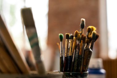 Sanatçının atölyesindeki iş yeri üzerine profesyonel resim için çeşitli boya fırçaları.