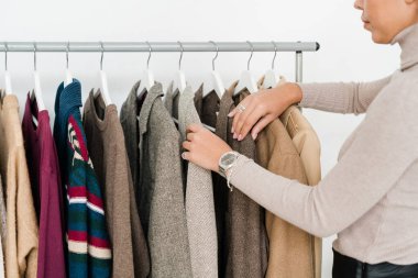 Genç, sıradan bir kadın yeni sezonluk kıyafet koleksiyonuna bakarken butikte askıda dikiliyor.