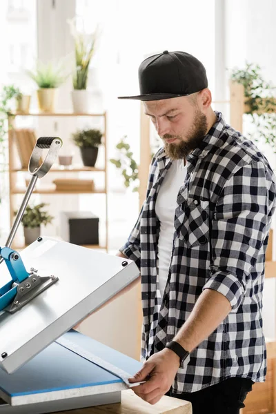 Serious Young Craftsman Holding Stripe Decor While Printing New Pet — ストック写真