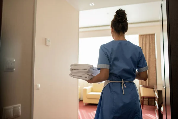 Vista Trasera Joven Camarera Morena Uniforme Llevando Una Pila Toallas — Foto de Stock