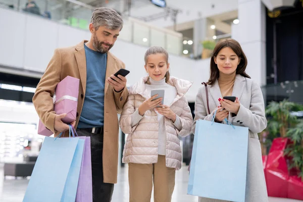 三个人组成的移动家庭一边在网上购物 一边用智能手机找东西买东西 — 图库照片