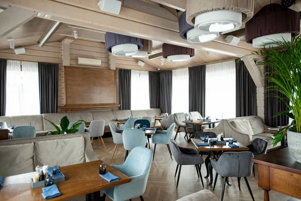 Etrafında yumuşak kadife koltuklar ve servis masaları olan modern restoranın lüks bir parçası.