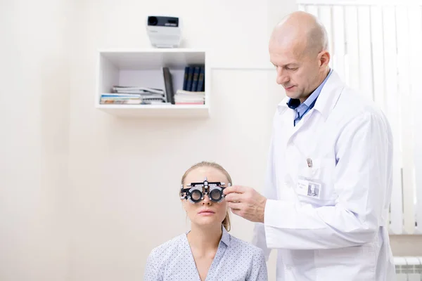 흰머리 의사가 환자의 시력을 조사하여 수정체를 안경에 넣는다 — 스톡 사진