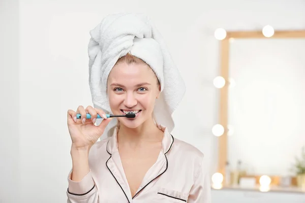 Mujer joven y saludable con cepillo de dientes cepillándose los dientes en el baño —  Fotos de Stock