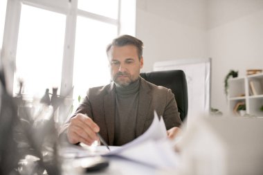 Ciddi mühendis kağıtları incelerken çizimlerden birine işaret ediyor ve gerekirse düzeltiyor.