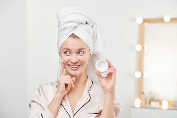 Kafasında Beyaz Havluyla Genç Güzel Bir Kadın Yüz Temizleme Kremini — Stok fotoğraf