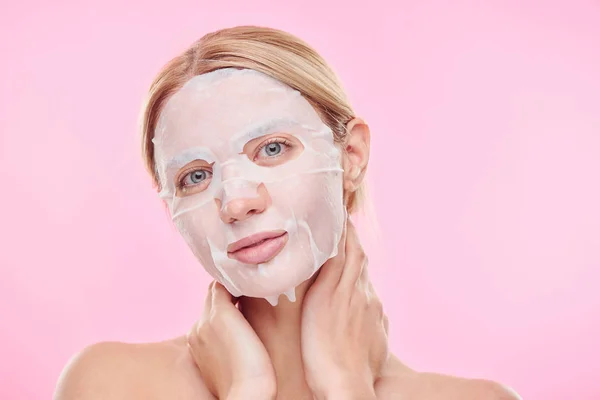 Blond Girl Textile Moisturizing Mask Face Looking You While Keeping — Stock Photo, Image