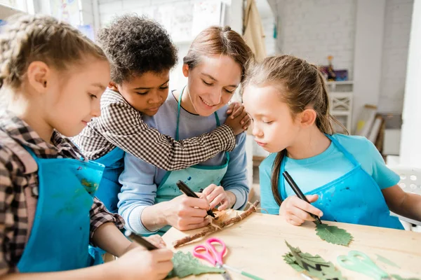 Liebevoller Schüler Umarmt Junge Lächelnde Frau Beim Zeichnen Oder Schreiben — Stockfoto