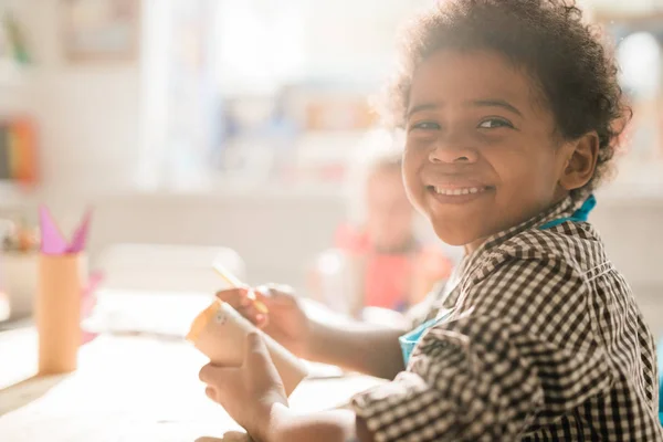 Leuke Vrolijke Schooljongen Met Opgerold Papier Zit Aan Het Bureau — Stockfoto