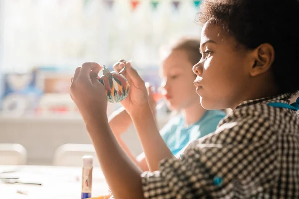 Niedlicher Afrikanischer Schuljunge Hält Handgemachte Dekorative Weihnachtsspielzeugkugel Vor Sich Während — Stockfoto