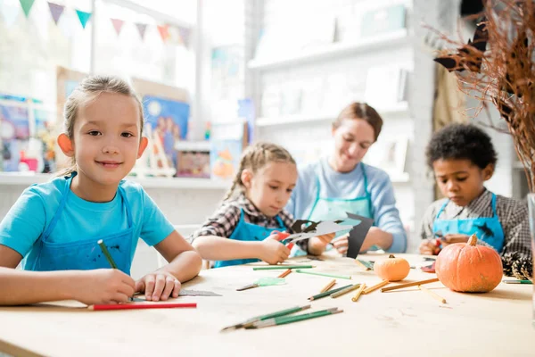 Lächelndes Schulmädchen Das Dich Ansieht Während Schreibtisch Sitzt Und Mit — Stockfoto