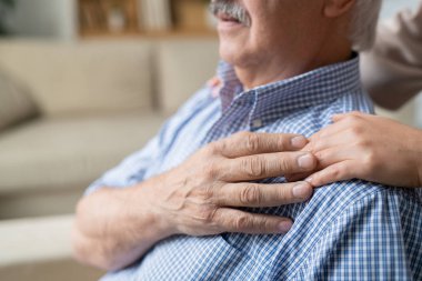 Hands of young daughter and that of her retired senior father on his shoulder as expression of love, affection and care