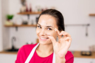 Hand of young woman holding star shaped cutter for homemade cookies while going to cut dough