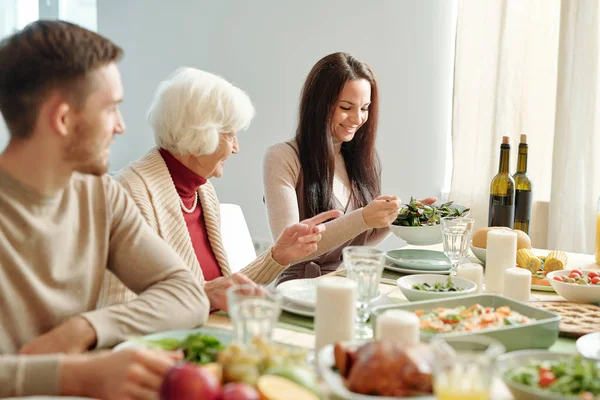 Happy Young Brunette Woman Putting Salad Plate Grandma Sitting Next — Stok fotoğraf