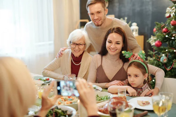 Cheerful Affectionate Family Sitting Served Festive Table Looking Smartphone Camera — Stockfoto