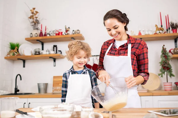 Happy Young Mother Whisking Raw Eggs Bowl Her Little Son — Stockfoto