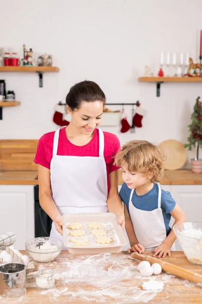 Young Mother Showing Her Son Raw Cookies Made Together Putting — Stockfoto