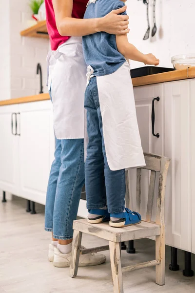 Menino Avental Cadeira Rasgada Pela Mesa Cozinha Enquanto Ajuda Sua — Fotografia de Stock
