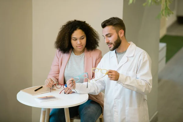 Young Confident Male Clinician Whitecoat Helping Female Patient Choose New — Stockfoto