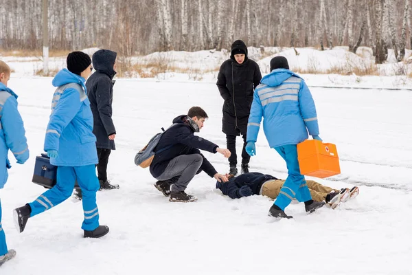 Tři Současní Zdravotníci Modré Uniformě Spěchají Nemocnému Ležícímu Sněhu Zatímco — Stock fotografie