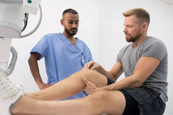Young Sportsman Activewear Complaining Sick Leg Knee While Showing Doctor — Stok fotoğraf