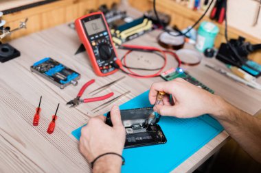 Ayrılmış akıllı telefonun küçük detaylarını düzeltirken tornavida kullanan cihaz tamir ustasının elleri