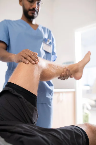 Contemporary Mixed Race Medical Specialist Uniform Holding Sick Leg His — Stock Photo, Image