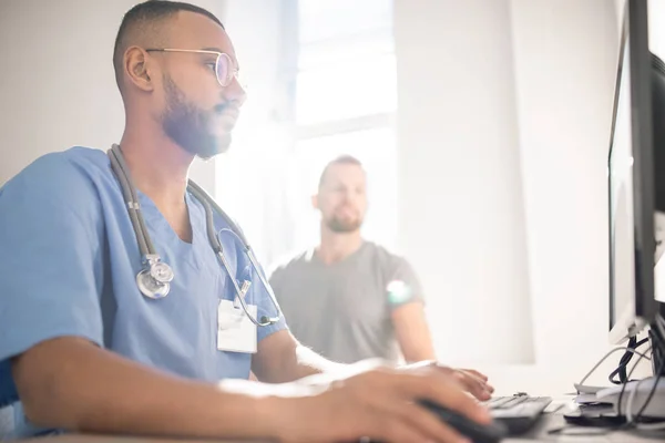 Médico Sério Com Estetoscópio Pescoço Sentado Frente Monitor Computador Preenchendo — Fotografia de Stock