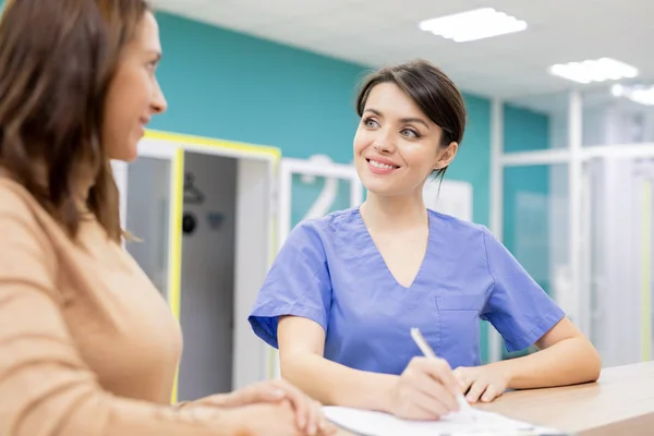 Erfolgreicher Arzt Uniform Lächelt Patientin Während Stift Über Ärztliches Dokument — Stockfoto