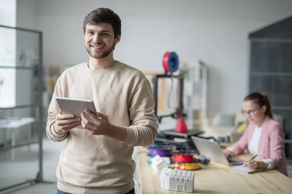 ネットサーフィンの同僚を背景にタッチパッドを使用してノートを作る若い成功したビジネスマン — ストック写真