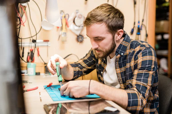 Jeune Réparateur Sérieux Penchant Sur Gadget Cassé Sur Table Tout — Photo