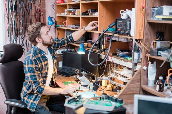 Junger Professioneller Reparateur Sitzt Sessel Neben Tisch Während Arbeitsmaterial Aus — Stockfoto