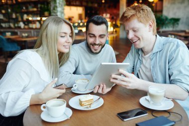 Neşeli genç adam derslerden sonra kafede kahve içerken arkadaşlarına garip videolar gösteriyor.