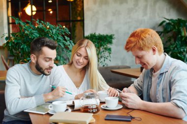 Zeki adamlardan biri derslerden sonra kız arkadaşıyla kafede ders verirken not defterindeki notlara işaret ediyor.